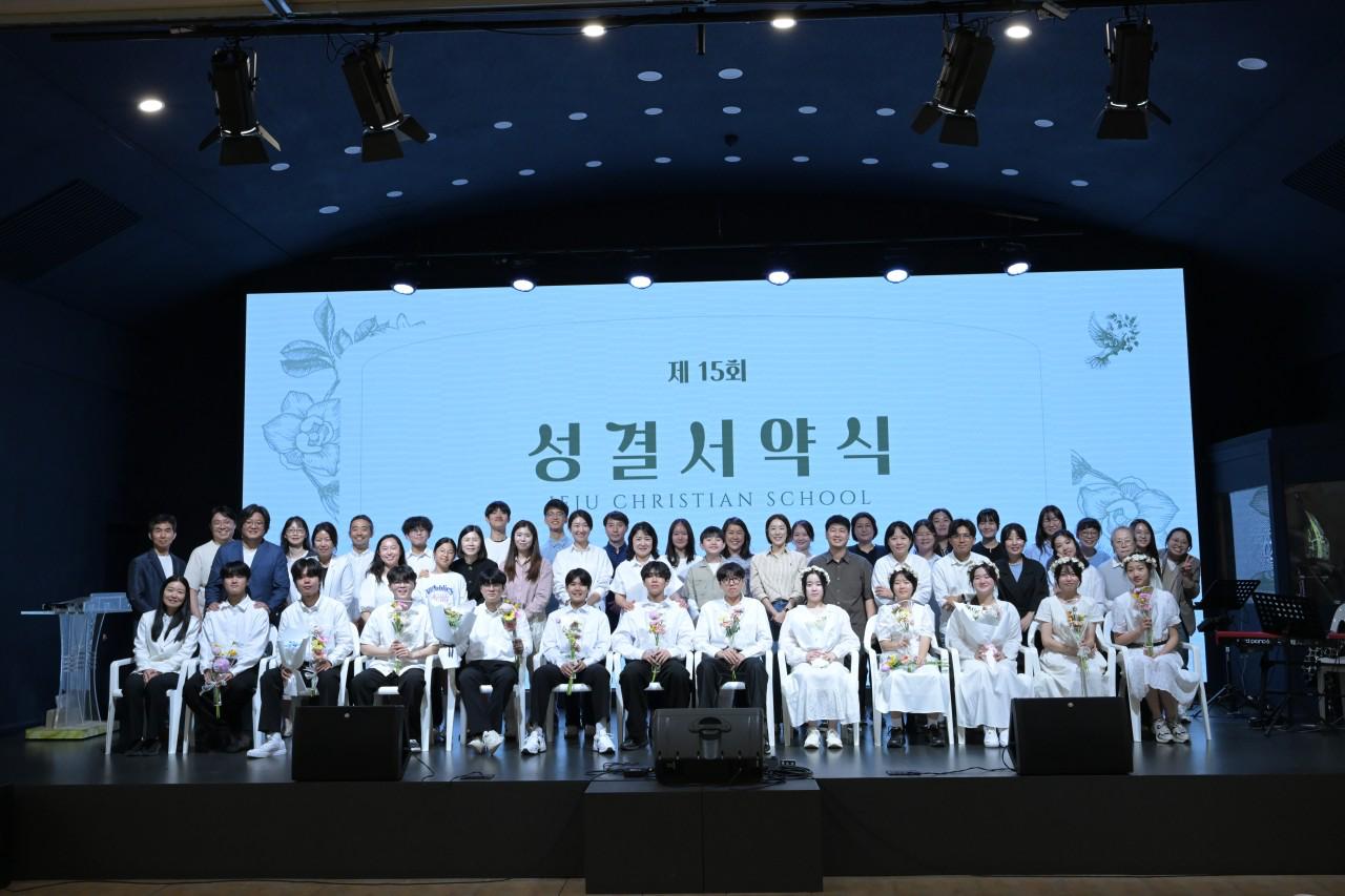 Students at the 15th Consecration Ceremony on stage with flowers